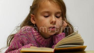 一个女孩读一本书的特写镜头。 一个年轻可爱的女孩低声读一本书